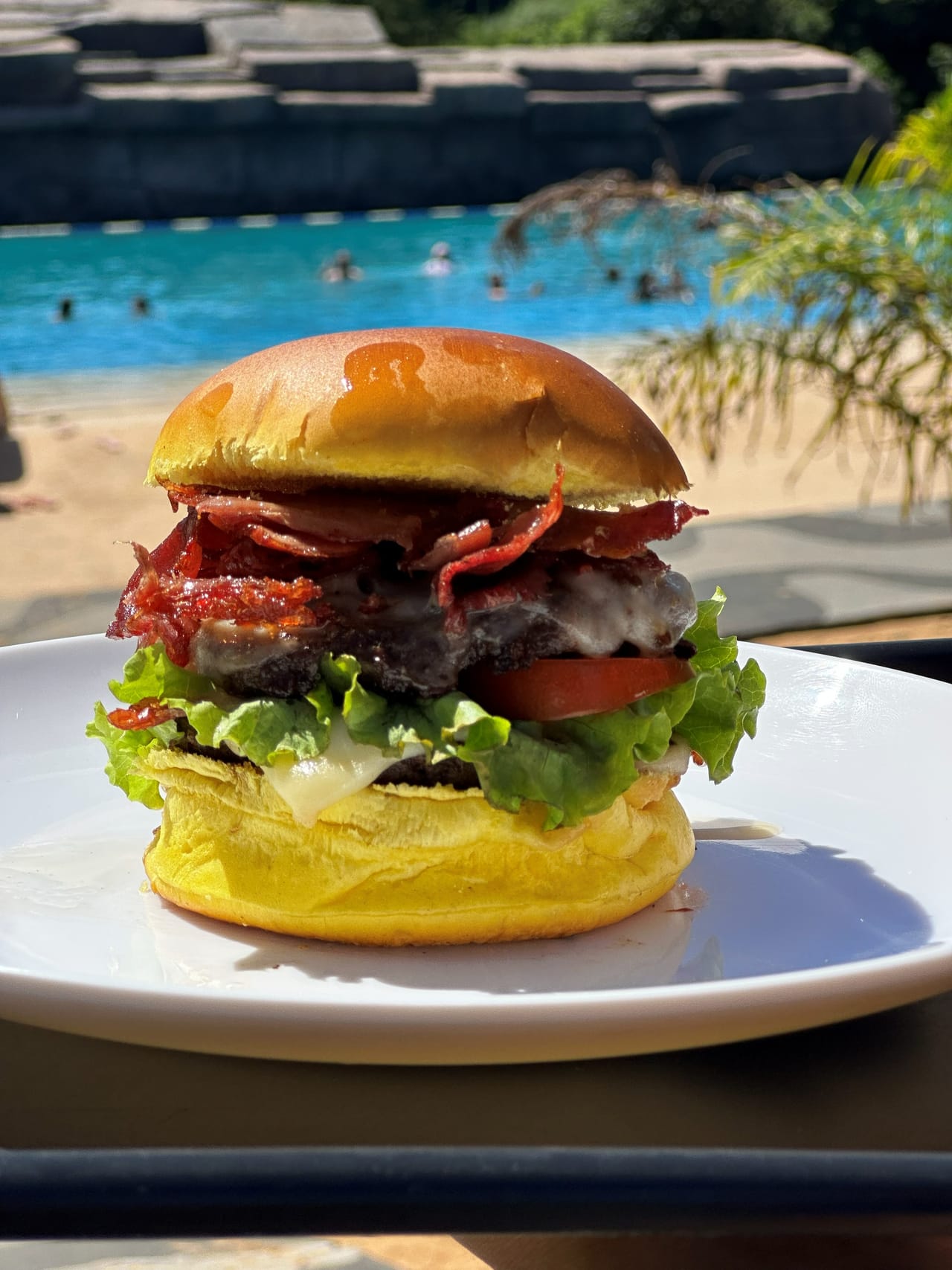 Hambúrguer artesanal servido na praça de alimentação do America Park, com a piscina ao fundo